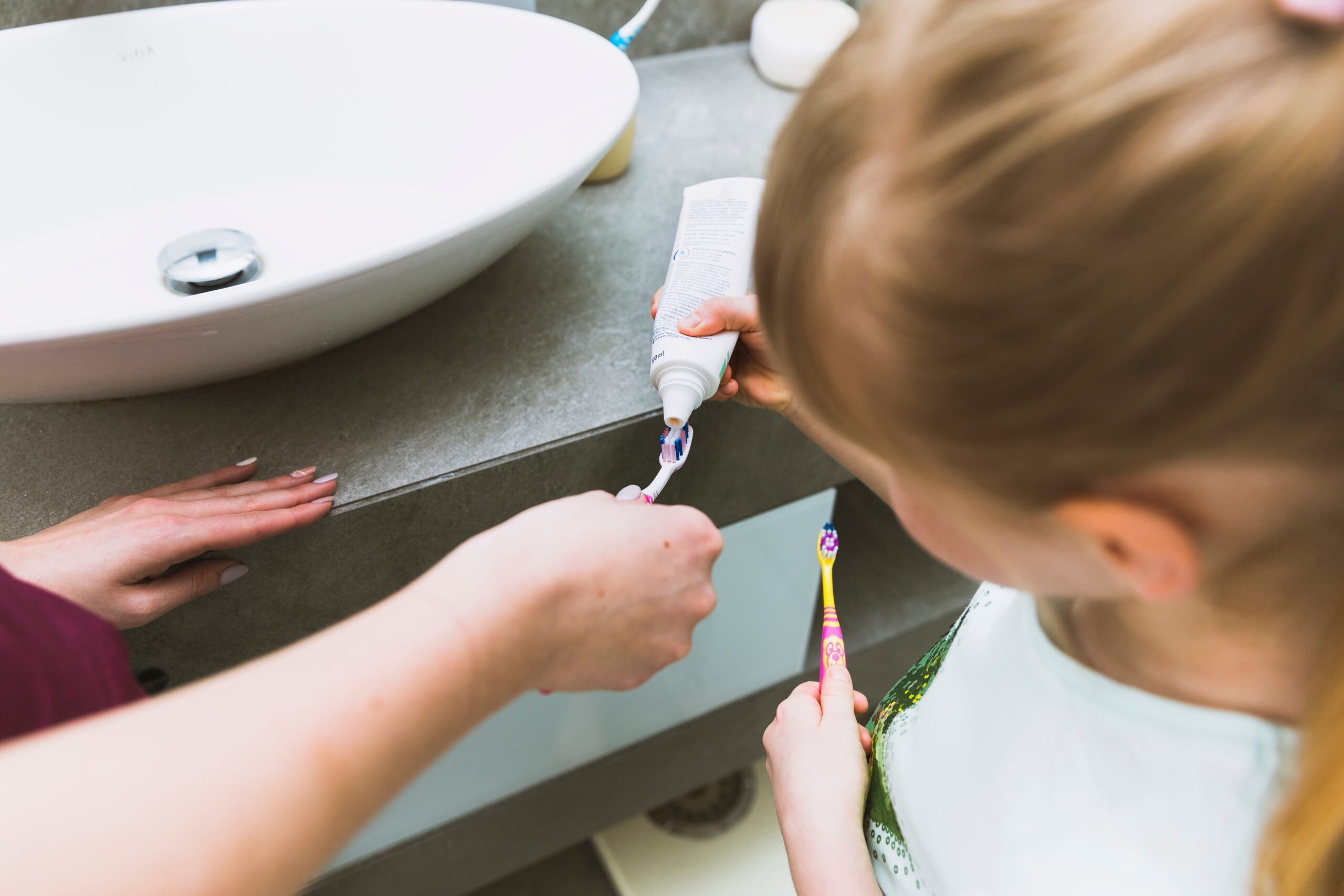 girl putting toothpaste brush mother 1 scaled