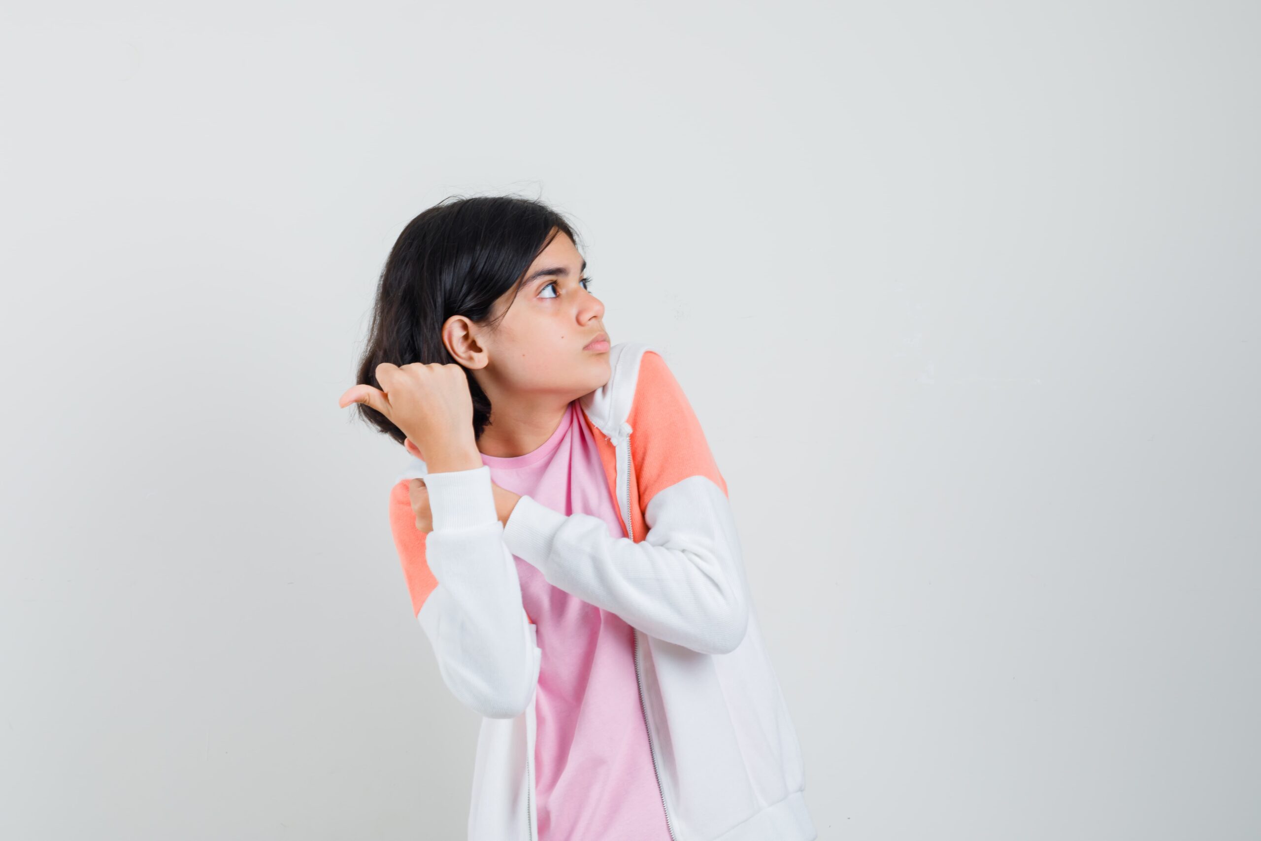 young lady pointing back jacket pink shirt looking scared 1 scaled