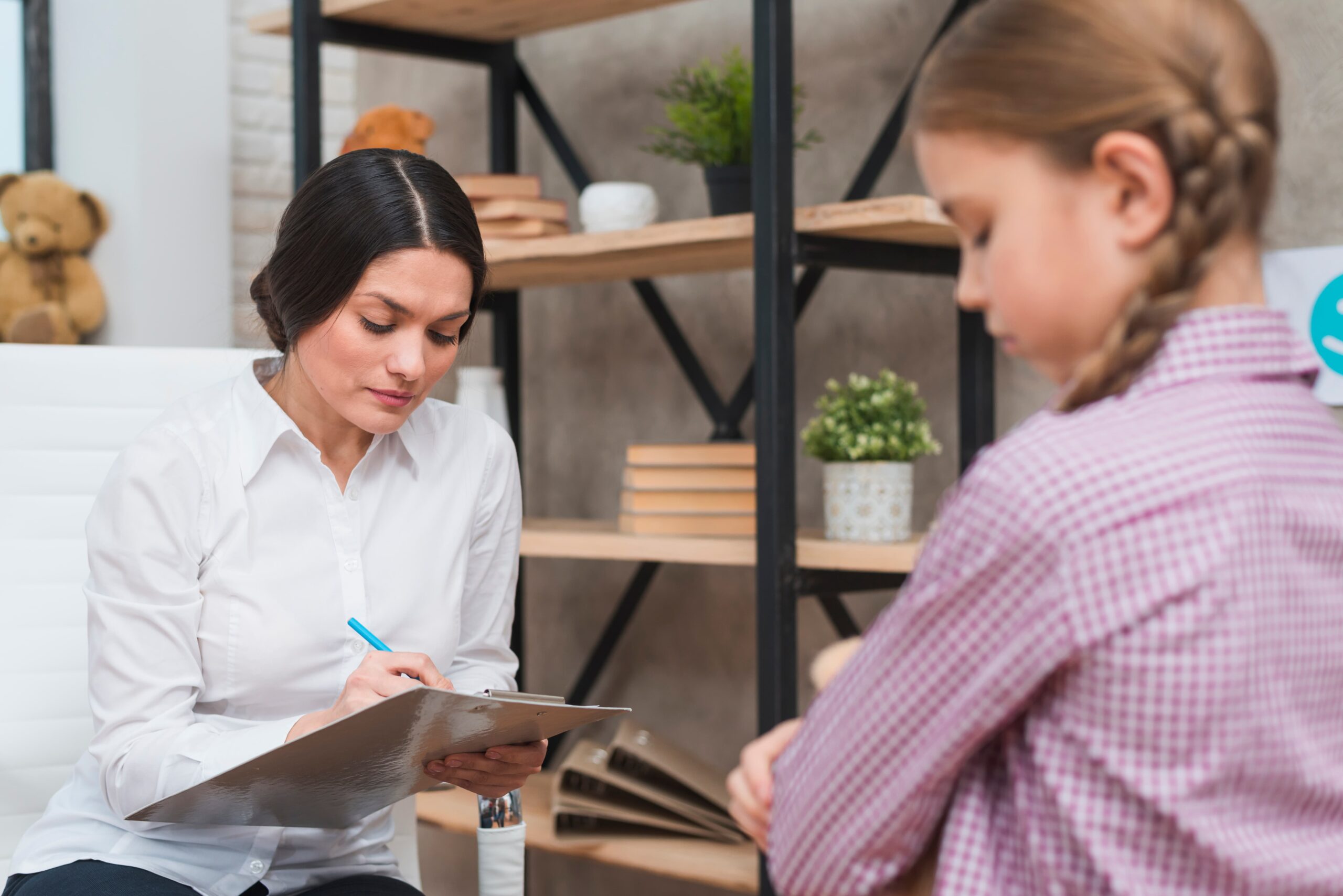 female psychologist taking notes clipboard therapy session 1 scaled
